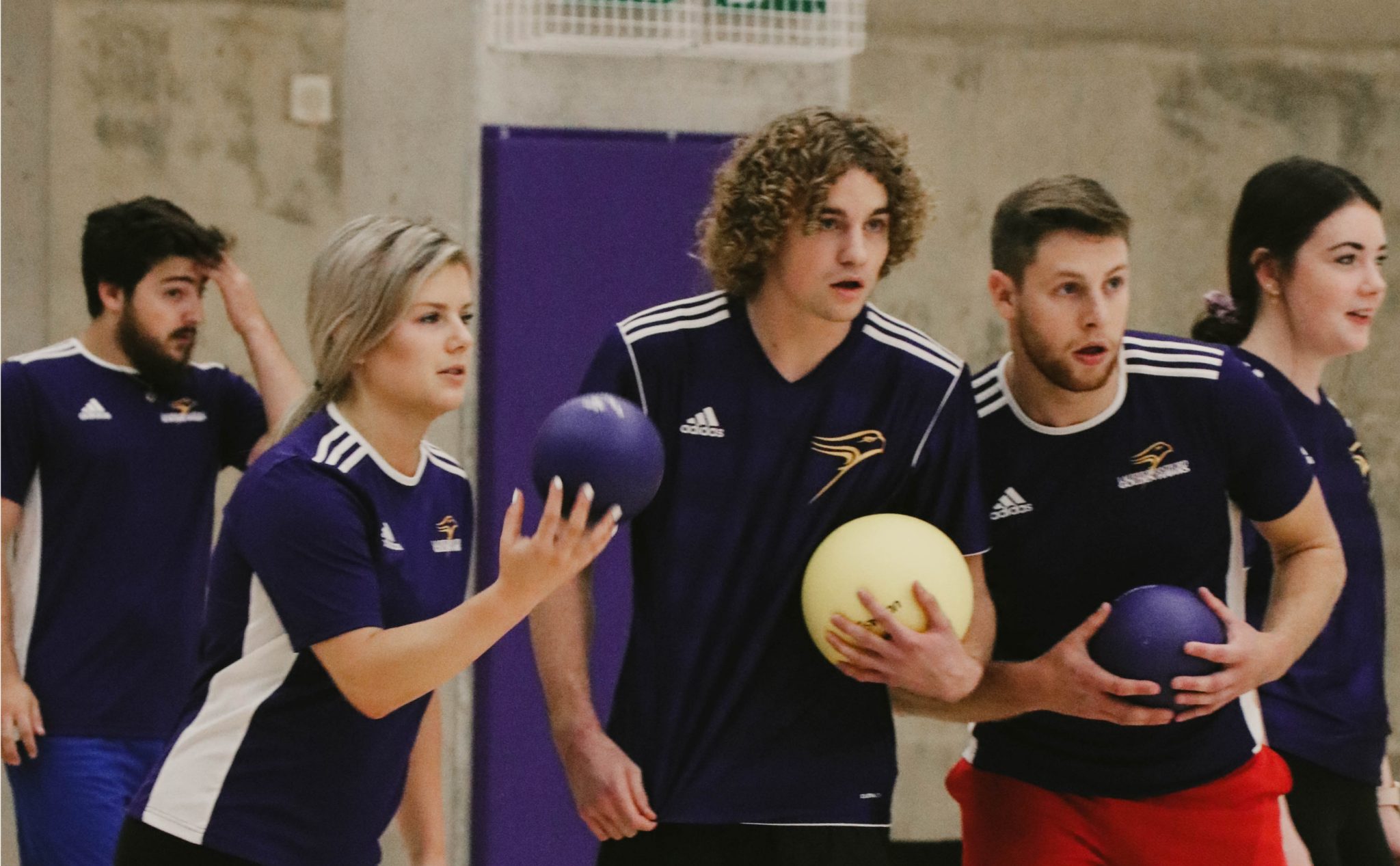 Laurier Brantford athletes gather with dodgeballs in hand mid-game, focusing on their opponents.