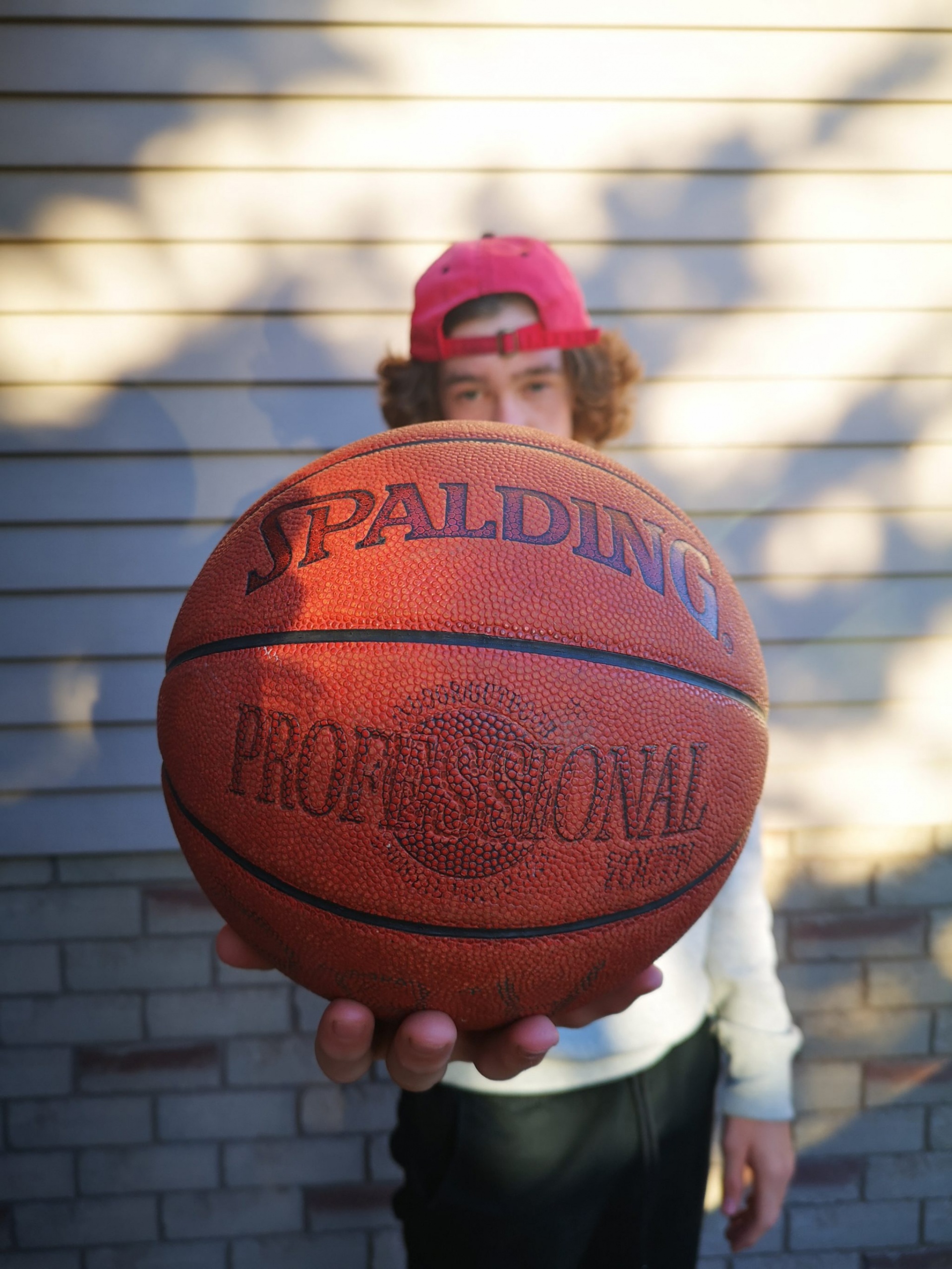 A young man holding a Spalding basketball out towards the camera