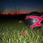 Black and red soccer ball in a field as the sun sets