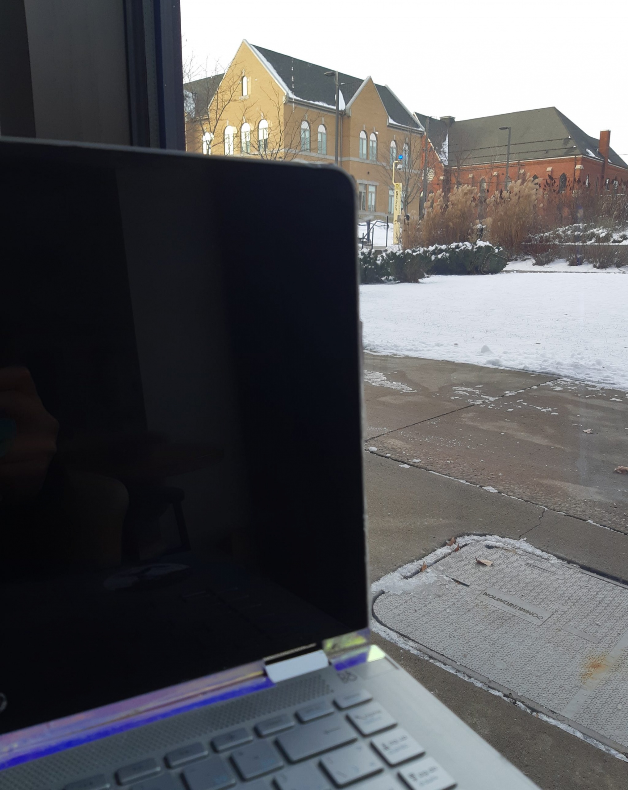 A laptop near a window facing the Post House residence building