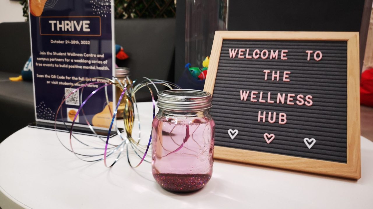 A letter board reading welcome to the wellness hub, and a jar with glitter settled at the bottom