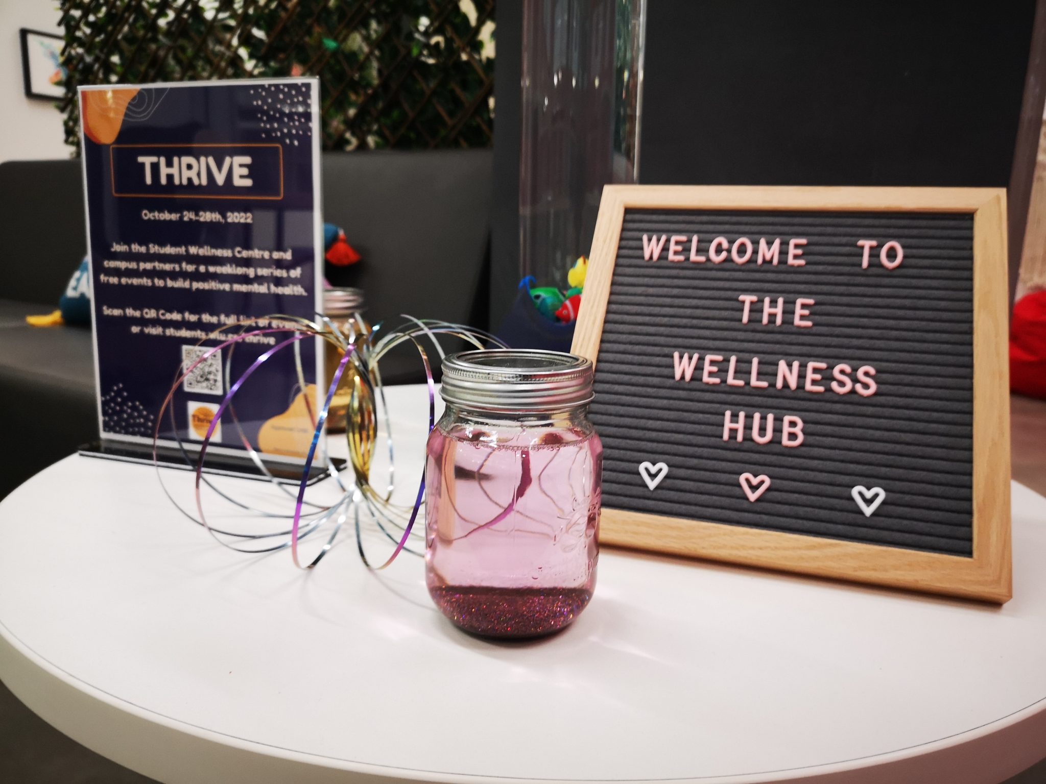 A letter board reading welcome to the wellness hub, and a jar with glitter settled at the bottom